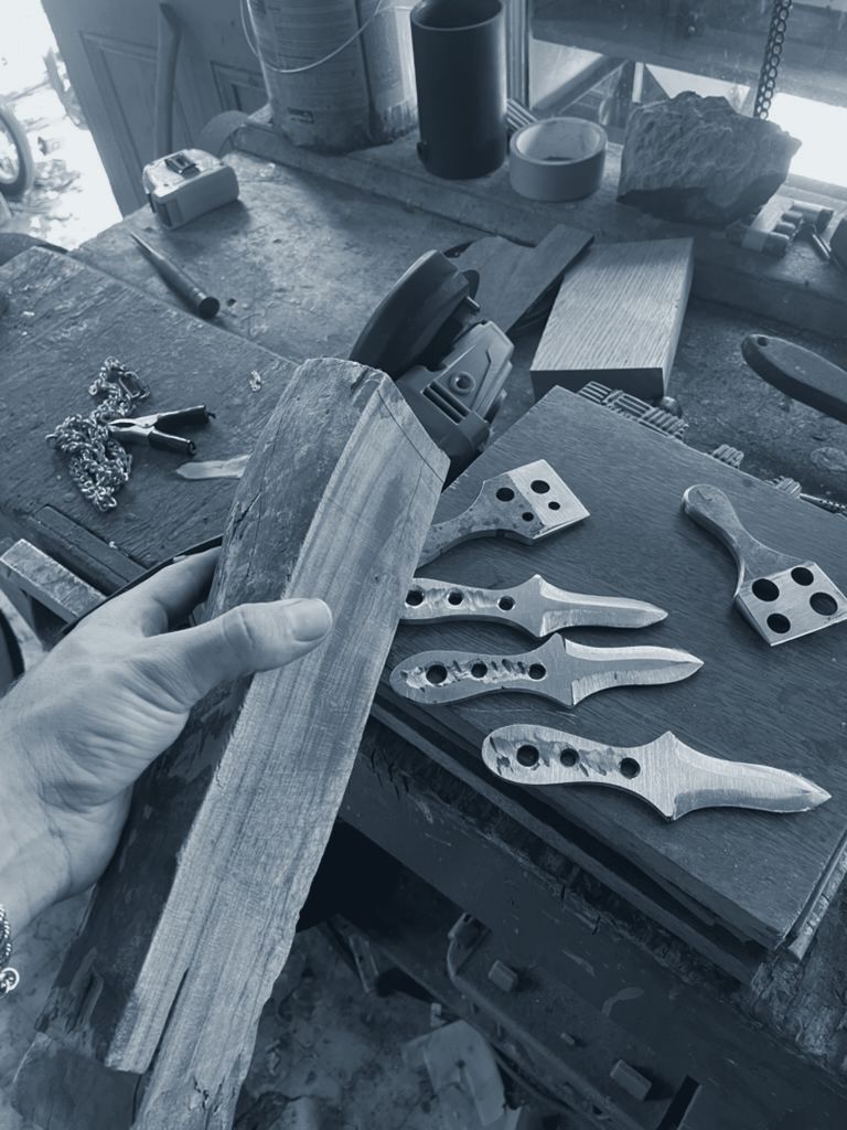 A hand holding a block of timber next to the finished blanks